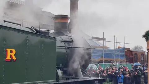 Didcot Railway Centre A crowd of people filming a steam locomotive on their phones and cameras as it sounds its whistle