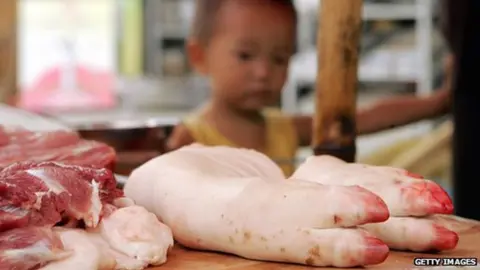 Getty Images A child stands next to pig trotters at a market on the outskirts of Chengdu