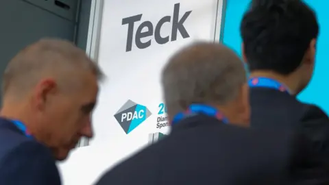 Reuters Men walk by a sign for Teck Resources