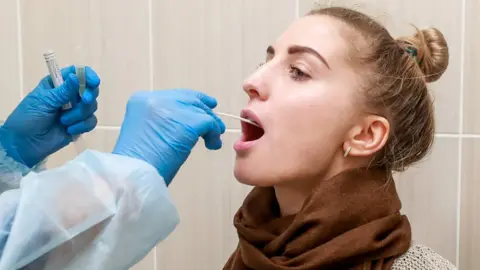 Getty Images Woman having throat swab taken