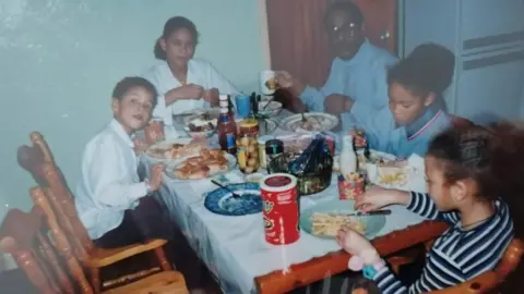 Ogogo family photo Ogogo as a child with his family eating at a table