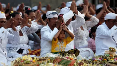 Reuters Worshipers are pictured wearing white and praying cross legged.