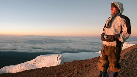 With a tool of the trade in hand, Dan enjoys the sunrise from the peak of Mt Kilimanjaro. (Audrey Scott)