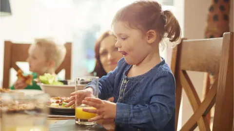 Getty Images A young girl takes a big drink of orange juice during a meal