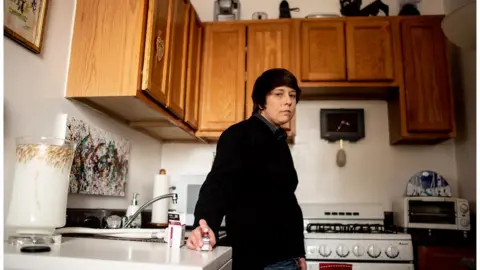 BBC Laura Marston stands in her kitchen, where she stores insulin in a quarter of her fridge