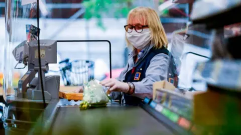 Getty Images A cashier wearing a mask at Aldi