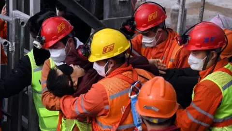 EPA A picture released by Xinhua News Agency shows a trapped miner being lifted from a gold mine in Qixia City, east China's Shandong Province, 24 January 2021.