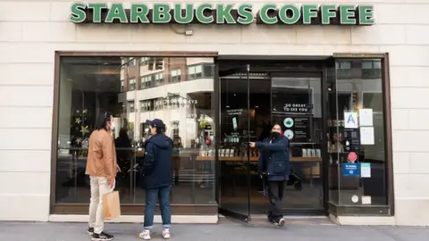 Getty Images Customers outside of a Starbucks coffee shop.