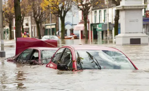 Getty Images Cars submerged on Cockermouth main street after the River Derwent burst its banks in 2009