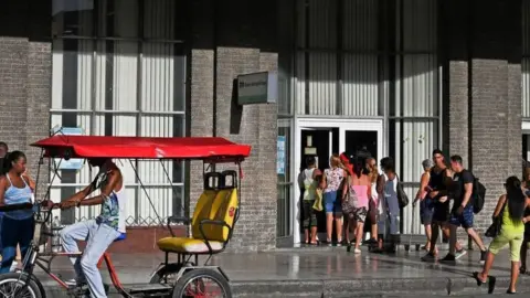 Getty Images Cubans queue outside a bank in Havana, on August 4, 2022.