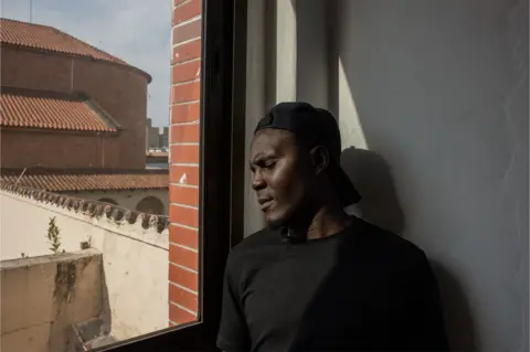 BBC Roman Friday stands by a window in São Paulo.