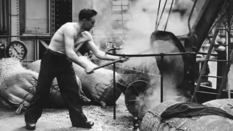 Getty Images A worker at the Guinness brewery at Saint Jame's Gate, Dublin, clearing a chute. 1953