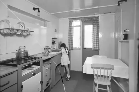 Historic England A young girl in the kitchen of a Uni-Seco prefabricated home in Brixton, London