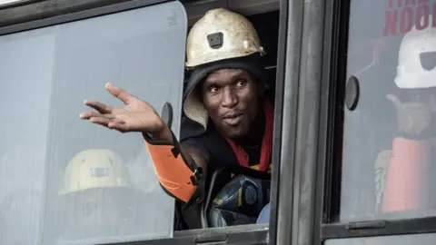 AFP / Getty Images  A rescued South African miner gestures out a bus window, 2 February 2018