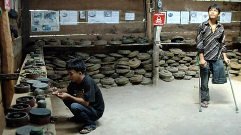 A Cambodian land mine victim surrounded by the deadly devices (Getty Images)
