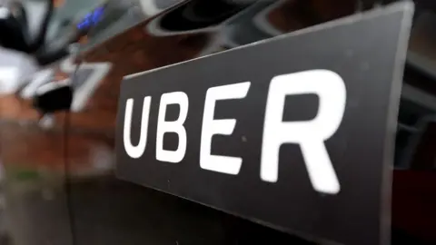 Getty Images A close up of a large Uber sticker on the side of a black car.