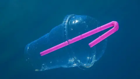Getty Images Plastic cup with straw floating in the ocean
