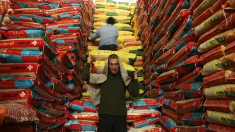Huw Evans picture agency A man carries bags of rice in a warehouse in China.