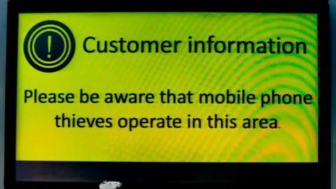 Getty Images Sign saying "Please be aware that mobile phone thieves operate in this area".