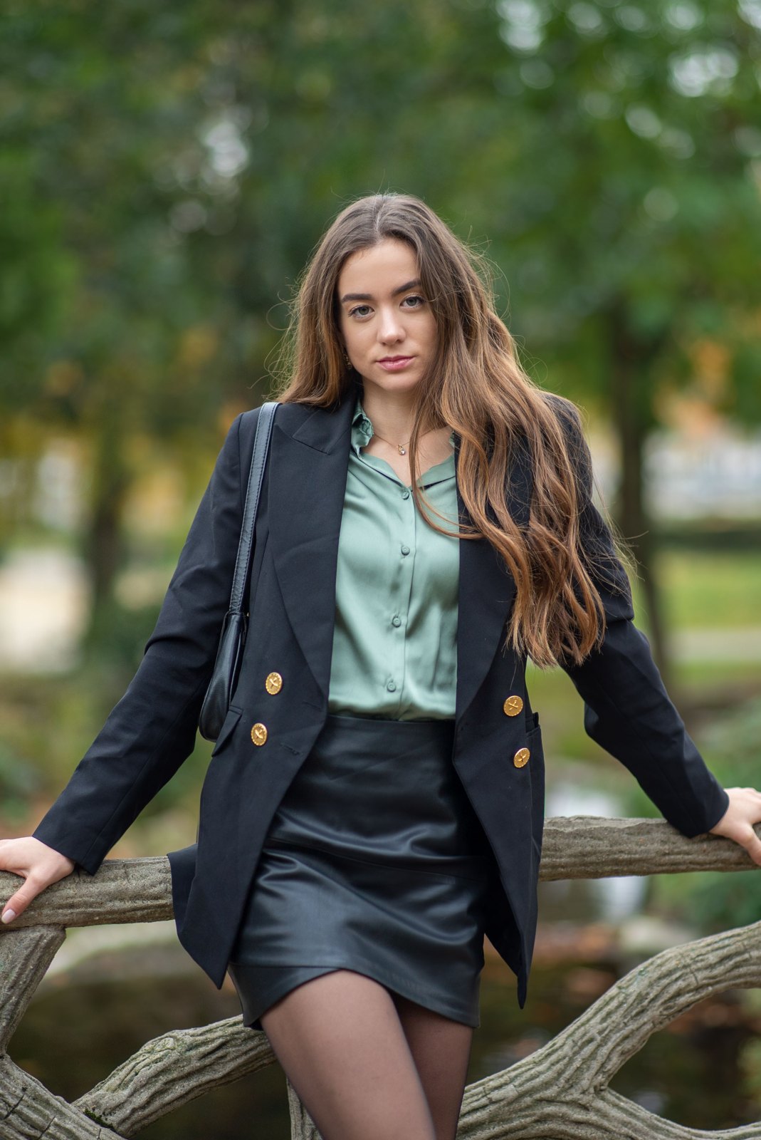 Woman wearing a black blazer and skirt with a green blouse outdoors